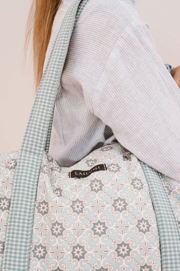 Detalle de una bolsa acolchada con estampado de baldosas y asa de cuadros vichy colgada al hombro