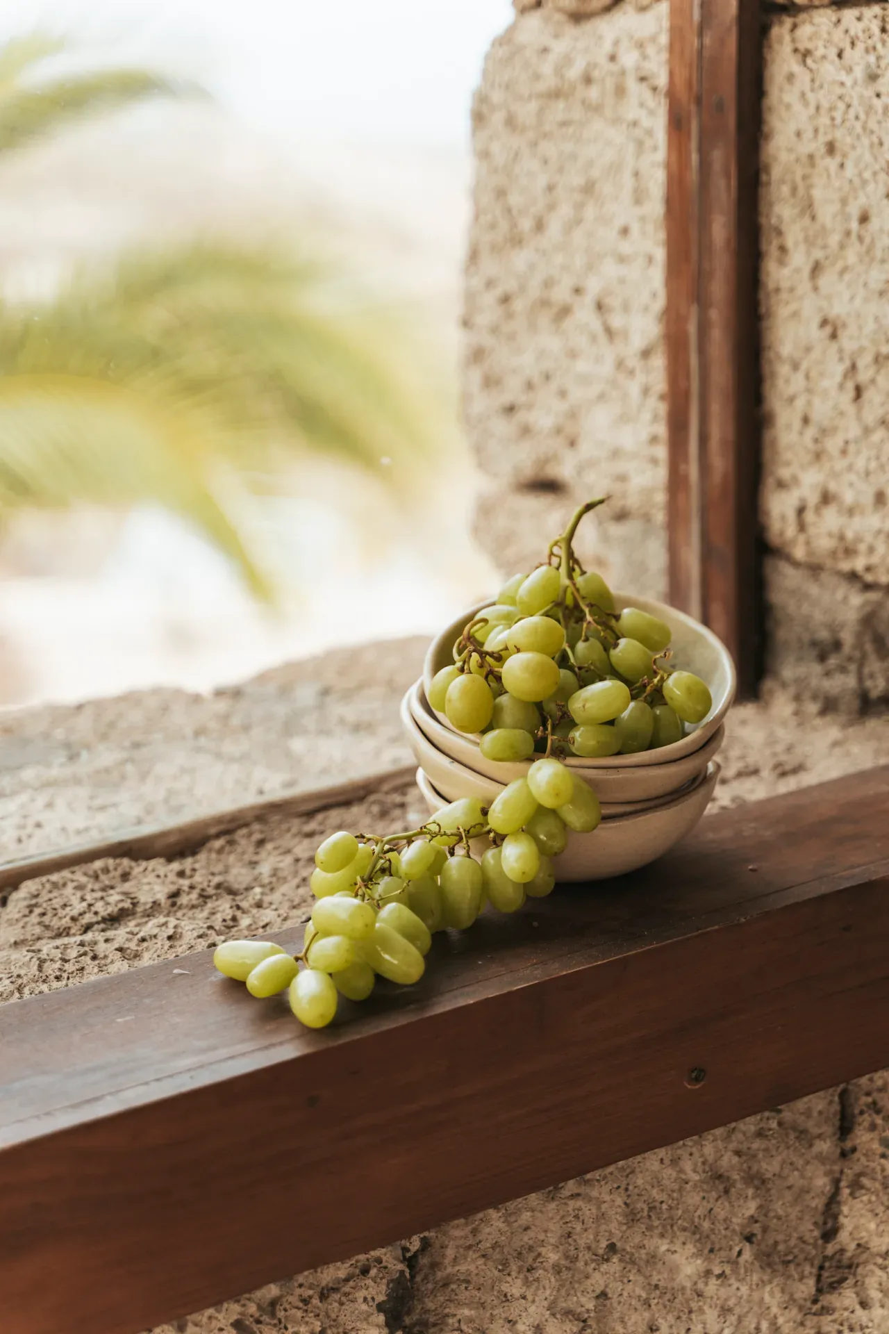 Racimo de uvas en unos cuencos junto a una ventana de piedra