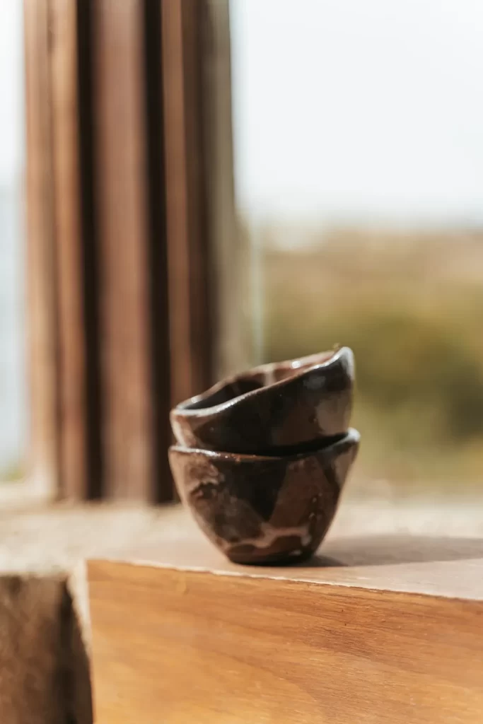 Dos cuencos de cerámica marrón esmaltada apilados sobre el alféizar de madera de una ventana