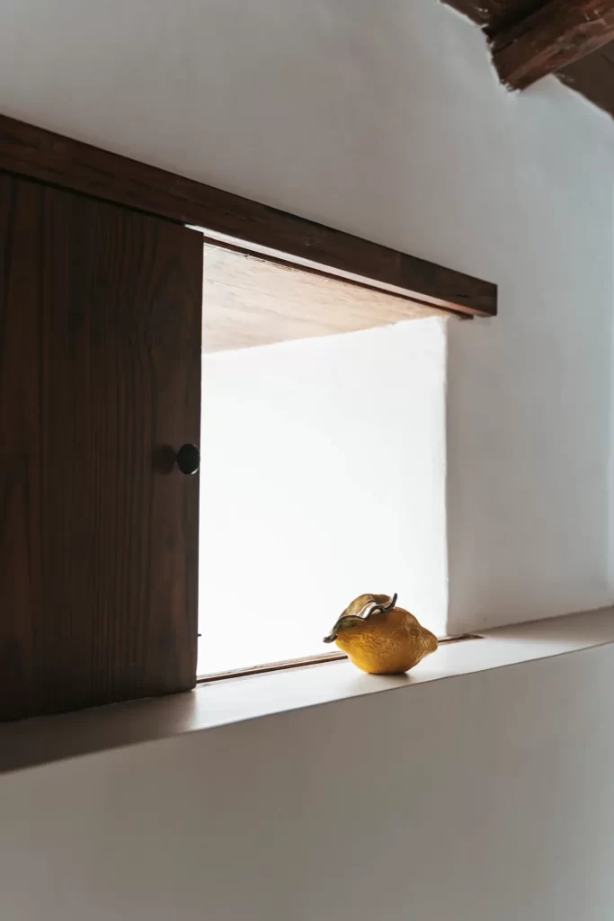Limón de cerámica sobre el alféizar de una ventana con contraventana de madera