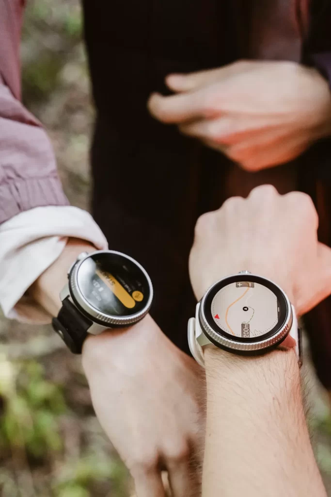 Dos muñecas con relojes deportivos, uno de ellos mostrando un mapa de la ruta en pantalla
