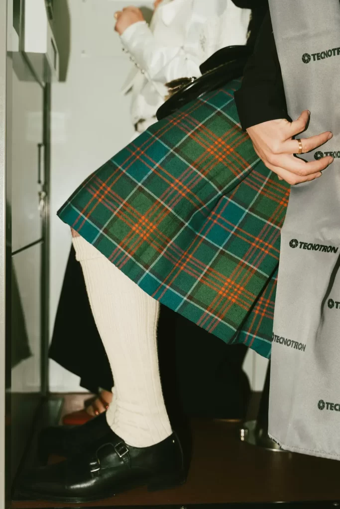 Detalle de falda escocesa verde, calcetines blancos y zapatos negros de hebilla