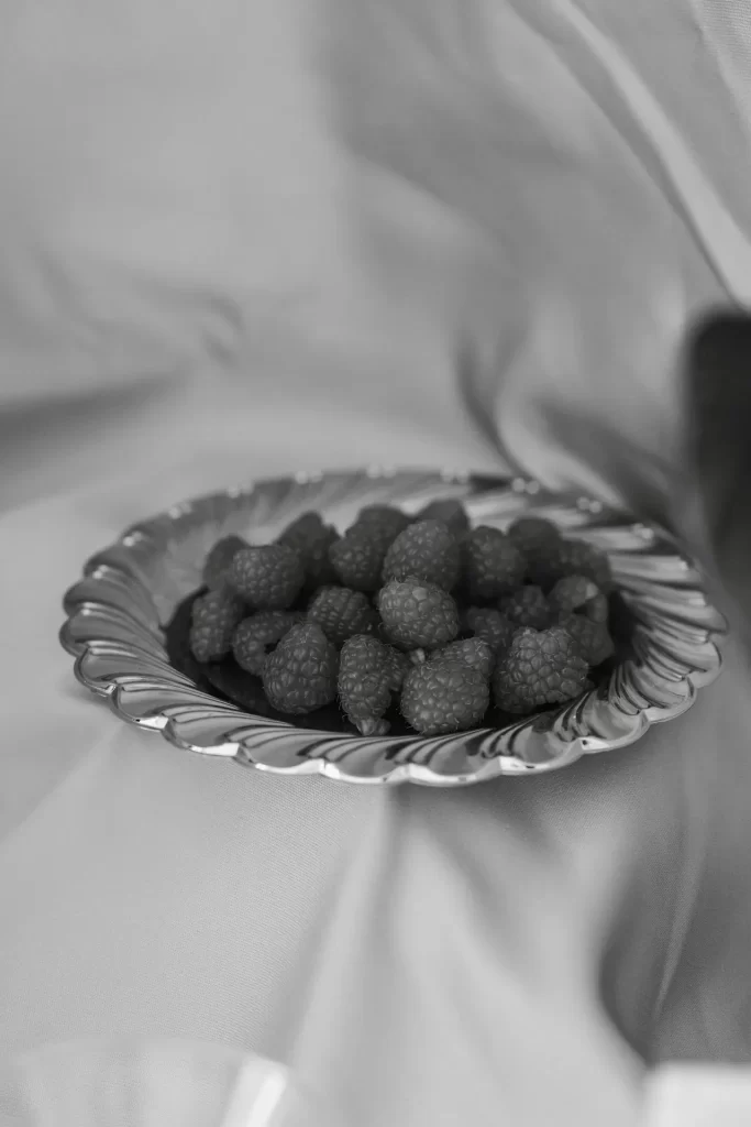 Frambuesas en un plato ondulado de metal sobre una tela satinada, en blanco y negro