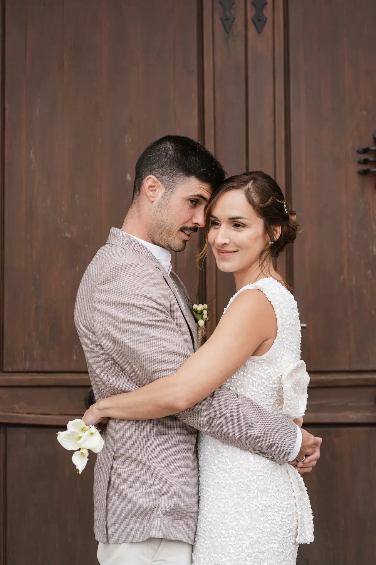 Pareja de novios abrazados ante una puerta de madera